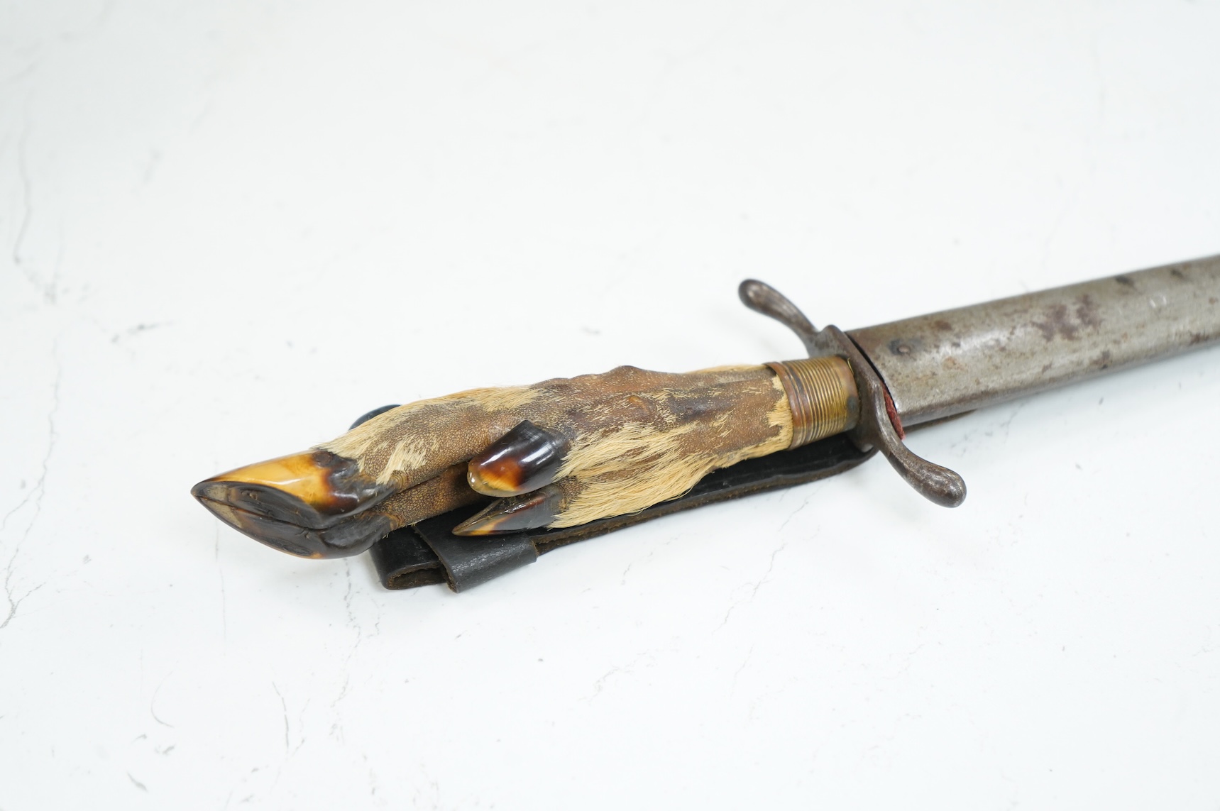 A First World War German Deer Hoof Fighting Knife, with a deer’s hoof grip, brass ferrell and steel cross guard, in original steel scabbard with leather belt loop mount, single edged blade with makers mark to one side; M